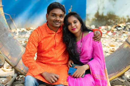 Happily married couple in traditional ethnic clothes sitting in a park.
