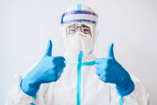 Happiness healthcare worker in PPE suit showing thumb up gesture while working in hospital during covid-19 pandemic. stock photo