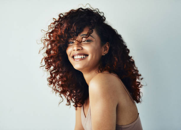 Happiness is the highest level of success Cropped shot of an attractive young woman posing alone against a gray background in the studio curly hair stock pictures, royalty-free photos & images