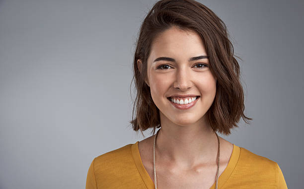 Happiness translates into beauty Studio portrait of an attractive young woman posing against a gray background brown hair photos stock pictures, royalty-free photos & images