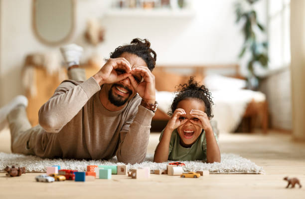 Happy african american family father with little son playing together, making binoculars with hands stock photo