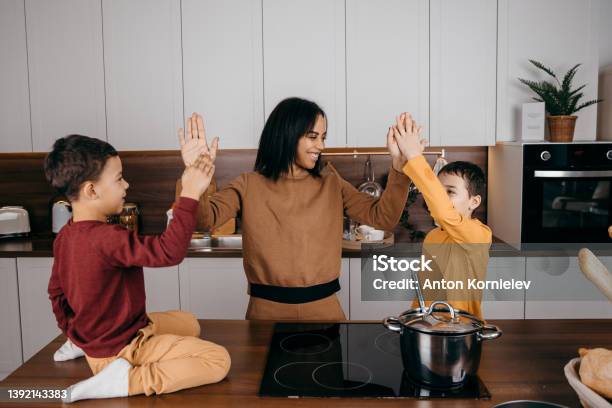 Happy african american family mom and two sons having fun cooking lunch in the kitchen