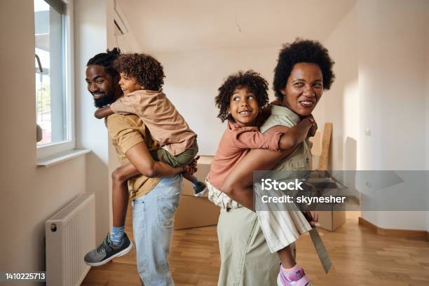 Happy African American family piggybacking at their new home.