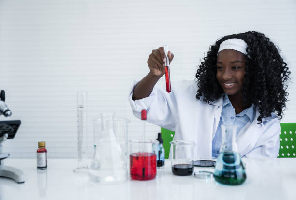 Happy african american student girl is learning and test science chemical with colorful liquid in tube test and beaker in laboratory room at to school. stock photo