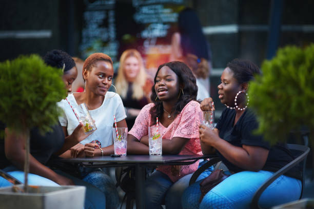Happy African American Women, friends sitting together at the outdoor restaurant at summer day stock photo