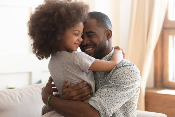 Happy african father holding embracing cute little child daughter Sweet moments of fatherhood concept, happy african father hold embrace cute little child daughter, smiling black family mixed race daddy and small kid hugging cuddling enjoying time together at home father stock pictures, royalty-free photos & images