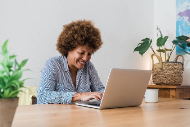 Happy african mature woman using laptop computer at home office - Focus in face stock photo
