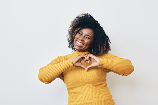 Happy African-American woman making heart with hands, smiling