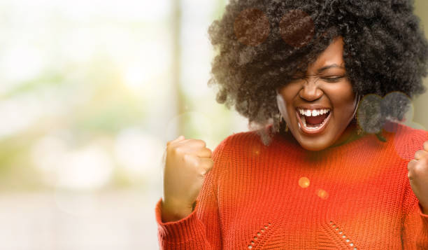 happy and excited celebrating victory expressing big success, power, energy and positive emotions. Celebrates new job joyful Beautiful african woman happy and excited celebrating victory expressing big success, power, energy and positive emotions. Celebrates new job joyful, outdoor voluptuous women images stock pictures, royalty-free photos & images