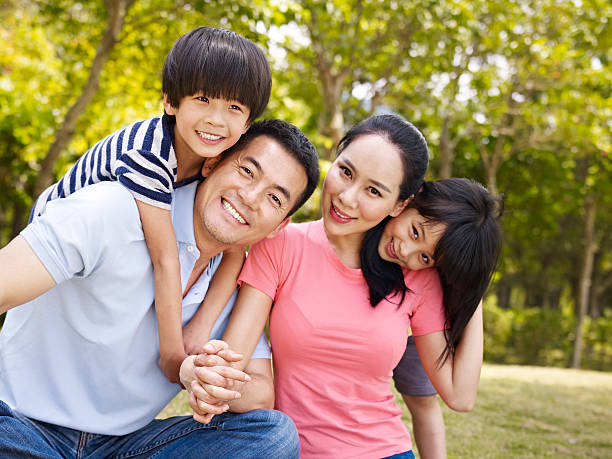 happy asian family in park asian family with two children taking a family photo outdoors in a city park. child korea little girls korean ethnicity stock pictures, royalty-free photos & images