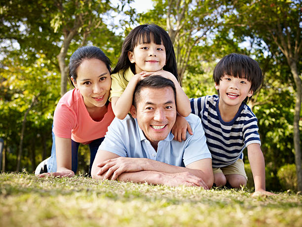 happy asian family outdoors in park happy asian family with two children taking a family photo outdoors in a park. child korea little girls korean ethnicity stock pictures, royalty-free photos & images