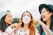 屋外でバブルガムを噛む楽しみを持つ幸せなアジアの友人 - 一緒に遊んで笑う若者 - 友情、ミレニアル世代と若者のライフスタイルの概念