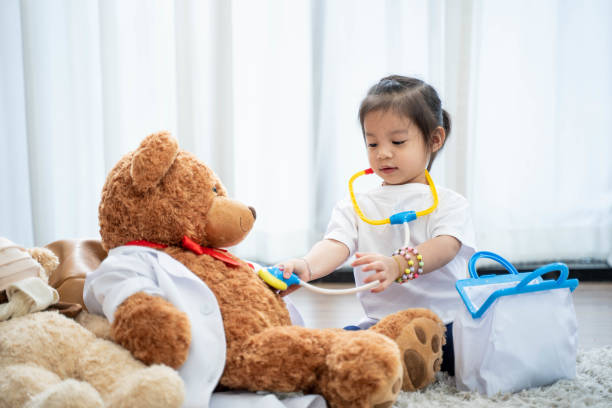 A happy Asian girl playing doctor or nurse listening to a stethoscope to the toy. A happy Asian girl playing doctor or nurse listening to a stethoscope to the toy. cute thai girl stock pictures, royalty-free photos & images