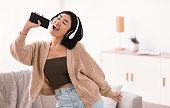 istock Happy asian lady singing using smartphone as mic 1284041637