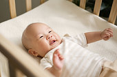 istock Happy Asian newborn baby smiling and laughing in crib 1372674428