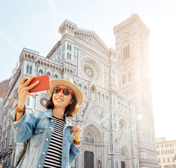 Happy asian woman taking selfie with her smartphone in the background of the Santa Maria Del Fiore Cathedral in Florence Happy asian woman taking selfie with her smartphone in the background of the Santa Maria Del Fiore Cathedral in Florence duomo santa maria del fiore stock pictures, royalty-free photos & images