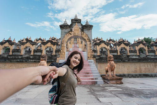 Happy Asian woman traveler smile in love holding hand boyfriend travel architecture pagoda ancient of Asia. Tourism south east Asia culture.