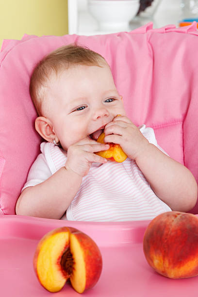 Happy baby eating fruit stock photo