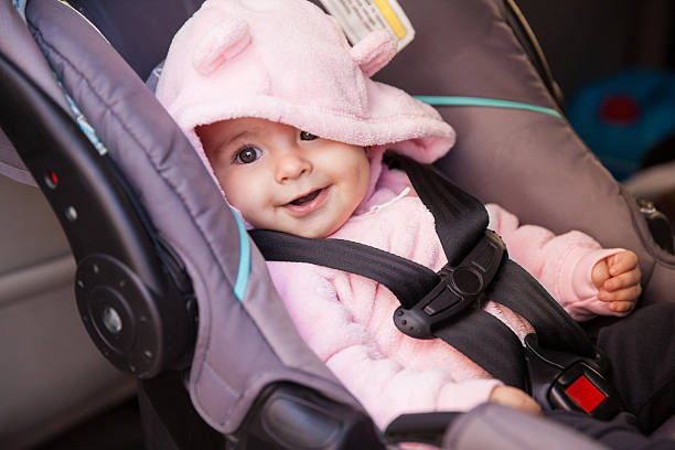 Happy baby girl in a car seat Portrait of a beautiful baby girl sitting on a car seat and smiling car safety seat stock pictures, royalty-free photos & images