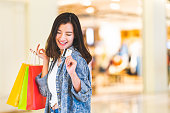 クレジット カードで美しいアジアの女性の幸せな笑顔は、ショッピング バッグ、ショッピング モールの背景にコピー スペースを保持します。買い物中毒の人、金持ちの女の子お金生活習慣