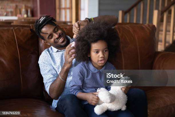 Happy biracial dad brush small daughter hair