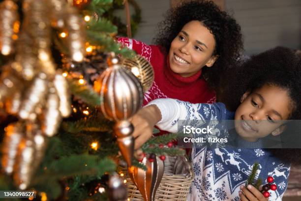 Happy biracial mom and daughter decorate Christmas tree