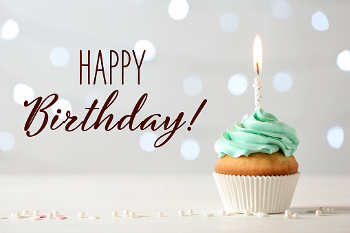 Happy Birthday! Delicious cupcake with burning candle on light background
