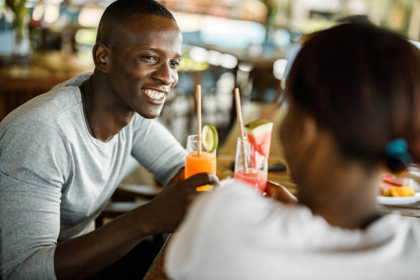 Happy black couple toasting with summer drinks at a cafe. stock photo