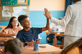 istock Happy black elementary student and his teacher giving high five during class at school. 1334049837
