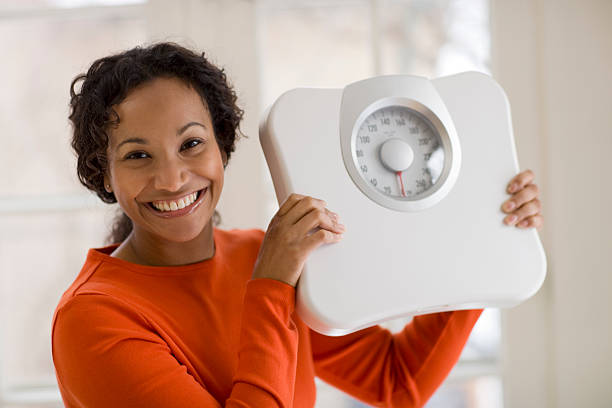 Happy Black woman holding scale stock photo