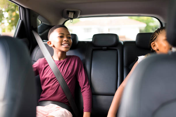Happy boy and sister in backseat of car seatbelts on stock photo
