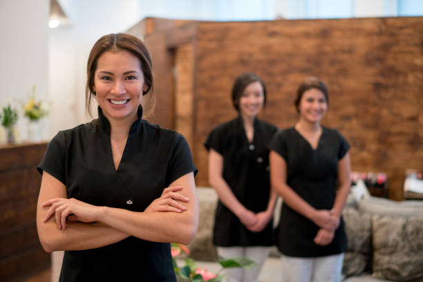 Happy business owner at a spa with a group of workers Portrait of a happy business owner at a spa with a group of workers looking at the camera smiling massage therapist stock pictures, royalty-free photos & images
