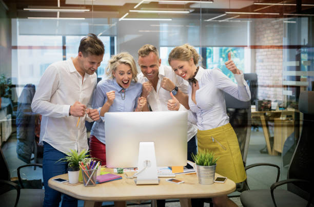Happy business team celebrate success at work Happy business team looking at computer and celebrate success at work website lainch stock pictures, royalty-free photos & images