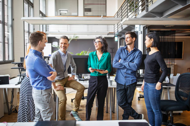 Happy business team having a standing meeting in office Group of multi-ethnic business people having a meeting in office. Businessmen and businesswoman having a standing meeting in modern office. business casual stock pictures, royalty-free photos & images