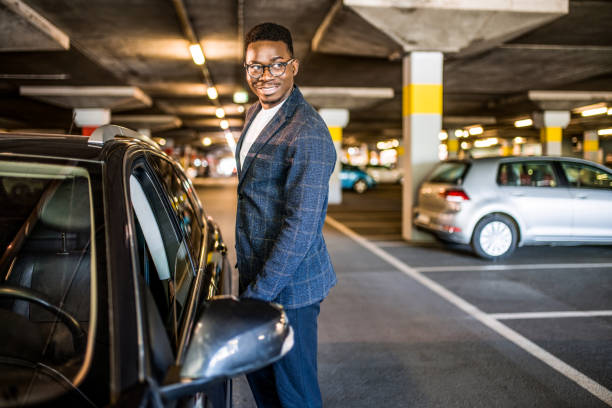 Happy businessman entering his car at car parking garage. stock photo