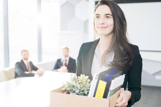 Happy Businesswoman Leaving Job Waist up portrait of smiling young businesswoman holding box of personal belongings  leaving office after quitting job, copy space quitting a job photos stock pictures, royalty-free photos & images