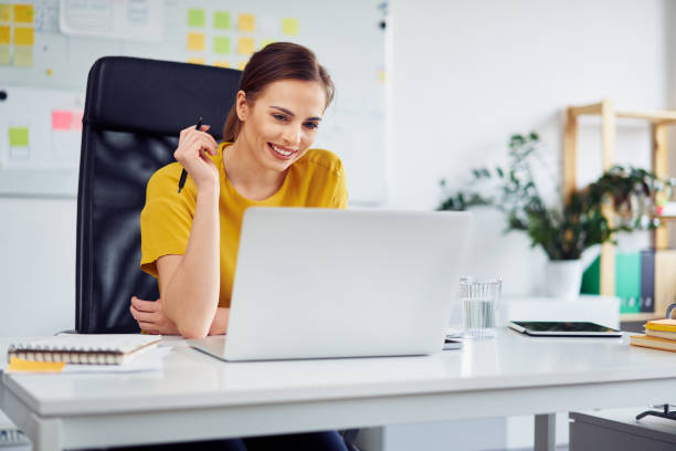 Happy businesswoman working on laptop at office stock photo