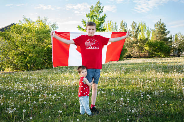 Happy Canada Day Celebration concept. Two Canadian brothers- toddler and teenager outdoor with Canadian flag.Front view stock photo