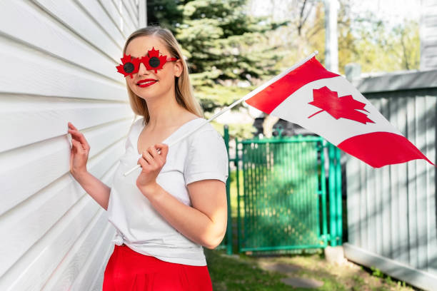 Happy Canada Day concept. Woman with Canadian flag smiling wearing fancy sunglasses looking to the camera. Proud Canadian stock photo