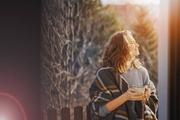 Happy cheerful beautiful curly young woman enjoying morning coffee and nature view on the terrace of a country house stock photo