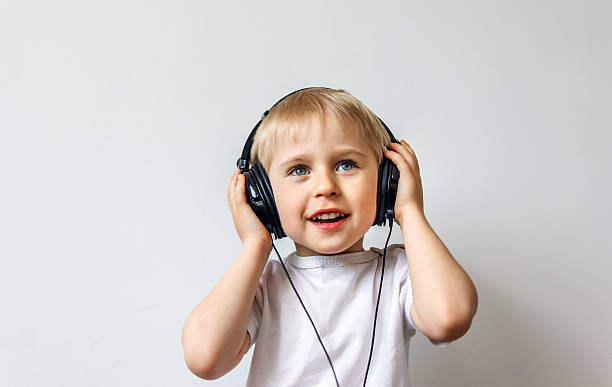 Happy cheerful boy with headphones listening to music stock photo