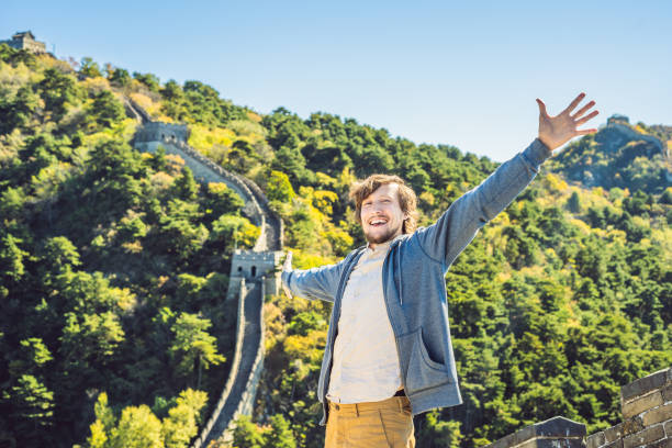 Happy cheerful joyful tourist man at Great Wall of China having fun on travel smiling laughing and dancing during vacation trip in Asia. Man visiting and sightseeing Chinese destination Happy cheerful joyful tourist man at Great Wall of China having fun on travel smiling laughing and dancing during vacation trip in Asia. Man visiting and sightseeing Chinese destination. jinshangling stock pictures, royalty-free photos & images