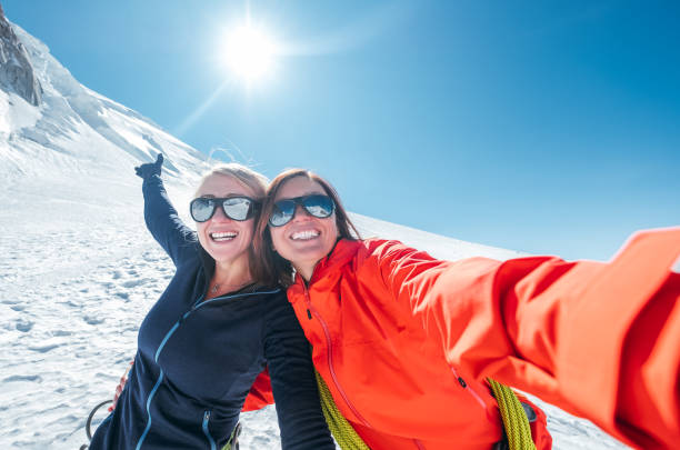Happy cheerful laughing embracing young female selfie portrait while they descending after a successful mountain top climbing. Happy active people concept image. stock photo