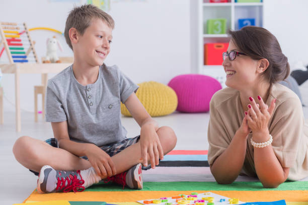 Happy child and school counselor Happy little child during during therapy with school counselor, learning and having fun together sitting on the floor in a colorful playroom school counselor stock pictures, royalty-free photos & images