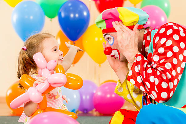 happy child girl and clown playing on birthday party stock photo