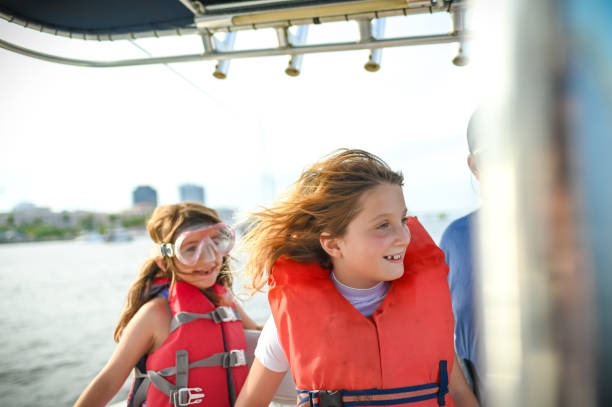Happy child, girl, in life jacket smiling on a sunny day on a boat on the water stock photo