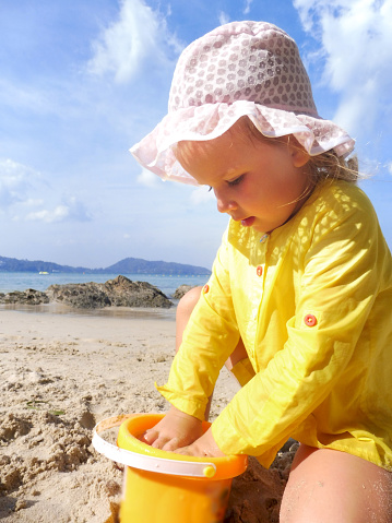 cute little girl playing with sand by the sea