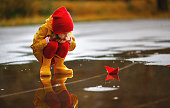 happy child girl with paper boat in a puddle in  autumn on nature