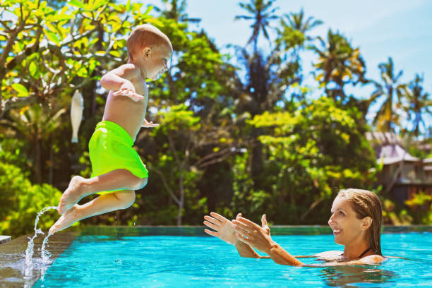 lyckligt barn hoppa till mor händer i poolen - bad catch bildbanksfoton och bilder
