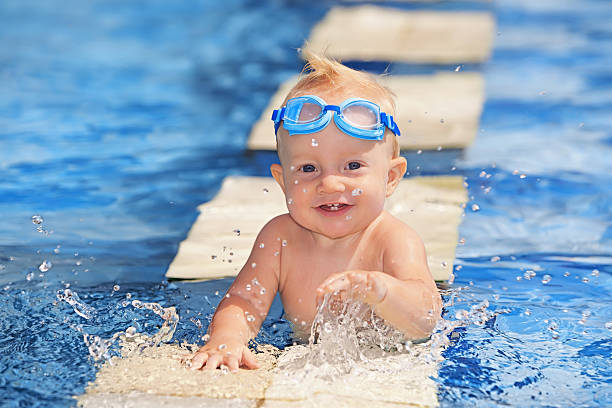 happy child playing with water splashes in pool - swimming baby stockfoto's en -beelden